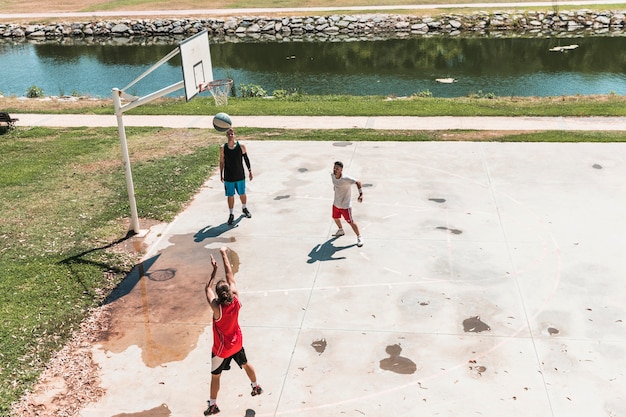 Three player playing basketball at outdoors court
