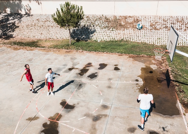 Three players playing basketball at outdoors court