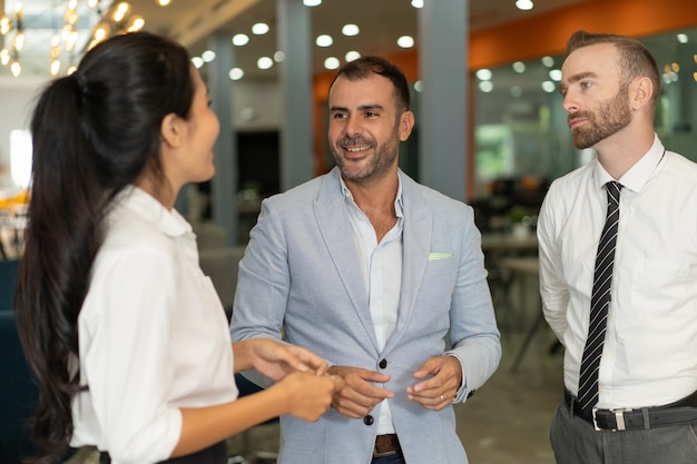 three positive business people chatting in office lobby