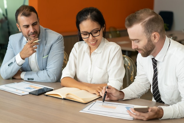 Three positive business people working with documents at desk