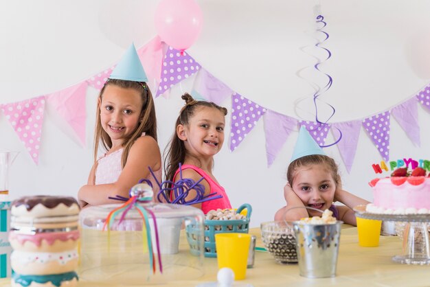 Three pretty smiling girls posing at birthday party