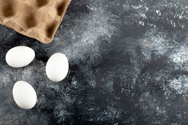 Three raw chicken fresh eggs on a marble surface. 