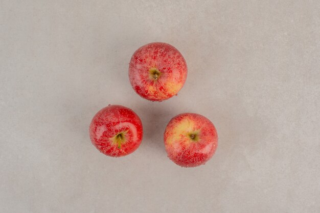 大理石の表面に3つの赤いリンゴ。