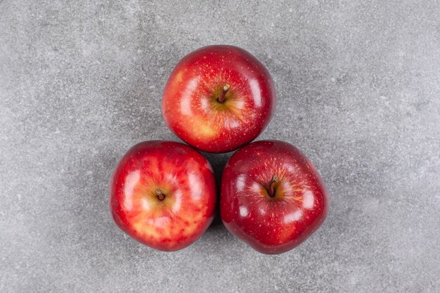 Three red apples on marble surface