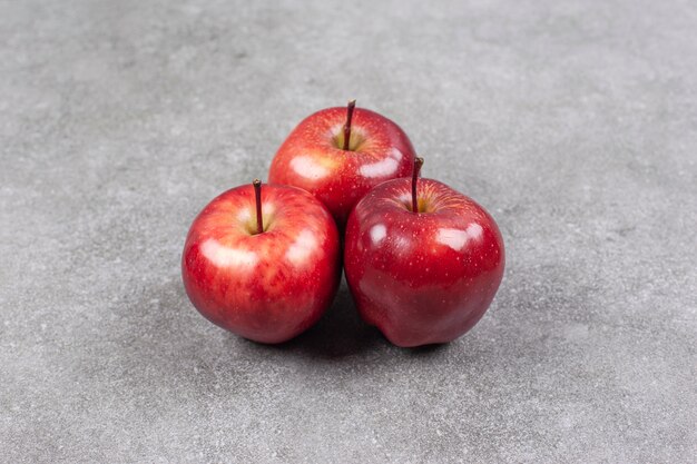 大理石の表面に3つの赤いリンゴ