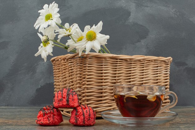 Three red candies with basket of bouquet and hot tea. 