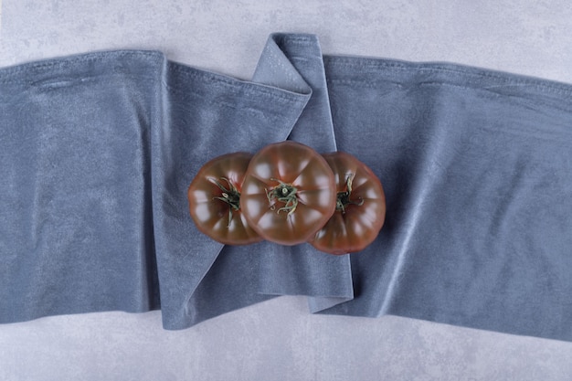 Free photo three ripe tomatoes on blue cloth.