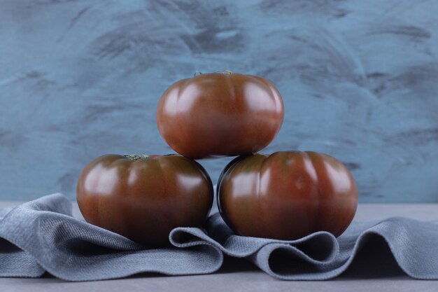 Бесплатное фото Три спелых помидора на синей ткани.