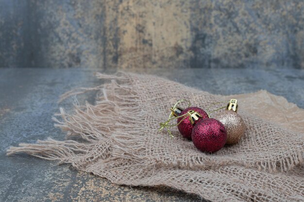 Three shiny Christmas balls on burlap.