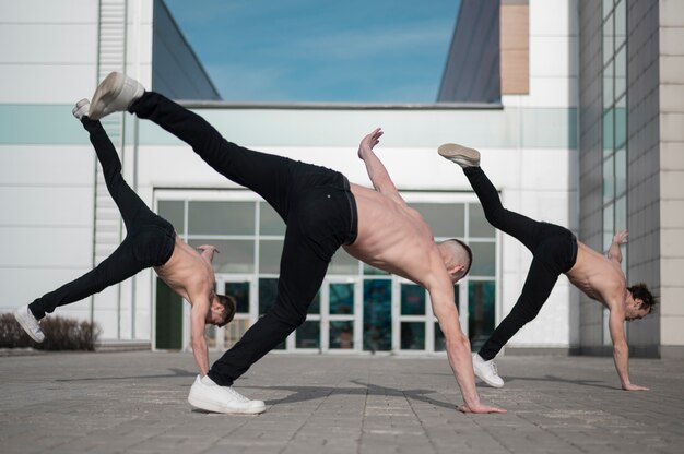 Three shirtless hip hop dancers practicing outside