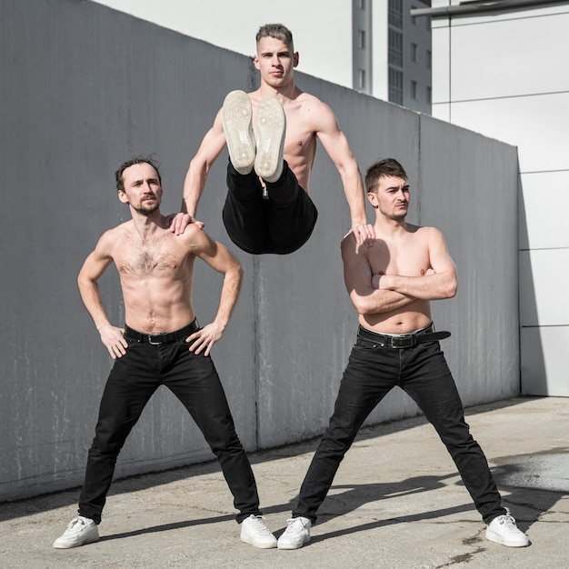 Free photo three shirtless hip hop performers posing together outside