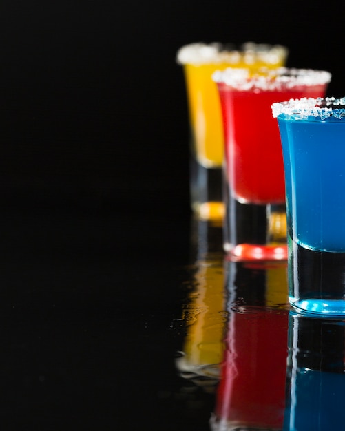 Free photo three shot glasses with colored cocktail and copy space