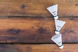 Free photo three shuttlecocks on wooden textured background