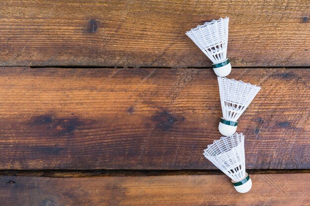 Three shuttlecocks on wooden textured background