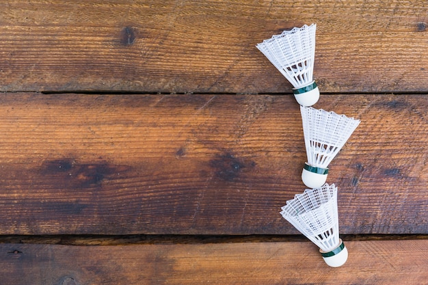 Three shuttlecocks on wooden textured background