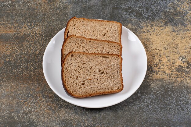 Three slices of black bread on white plate