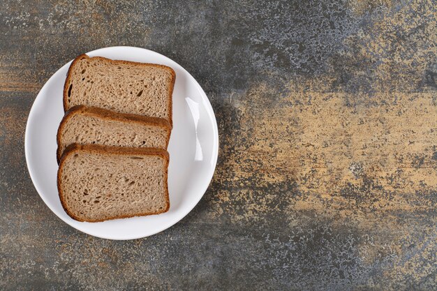 Three slices of black bread on white plate.