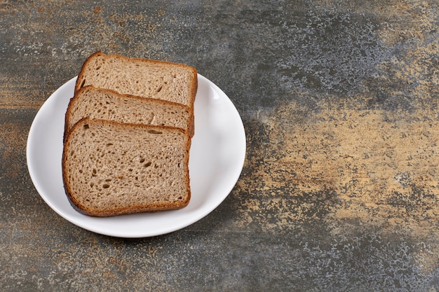 Free photo three slices of black bread on white plate.