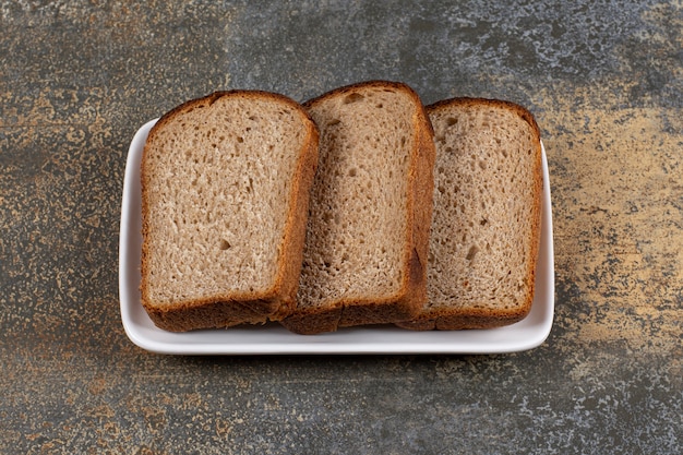 Three slices of black bread on white square plate