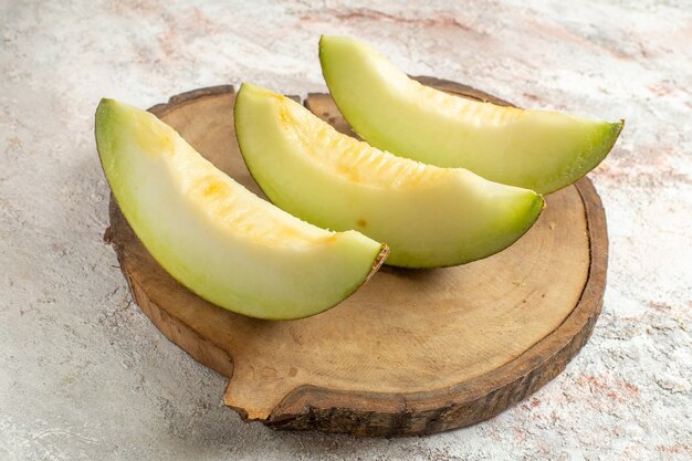 Three slices of melon on wooden platter on marble