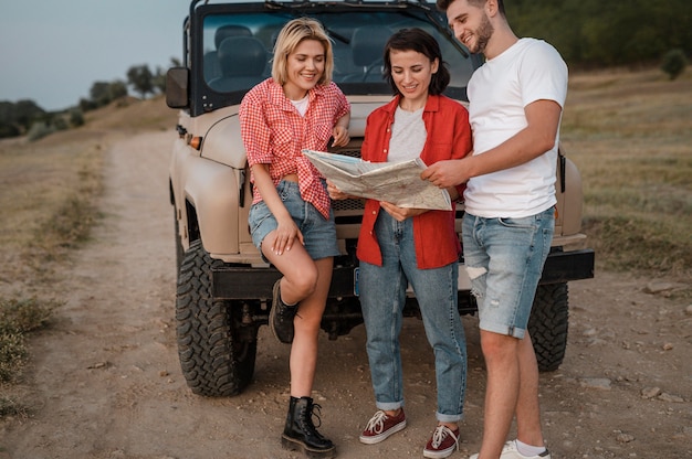 Tre amici smiley che controllano la mappa durante il viaggio in auto