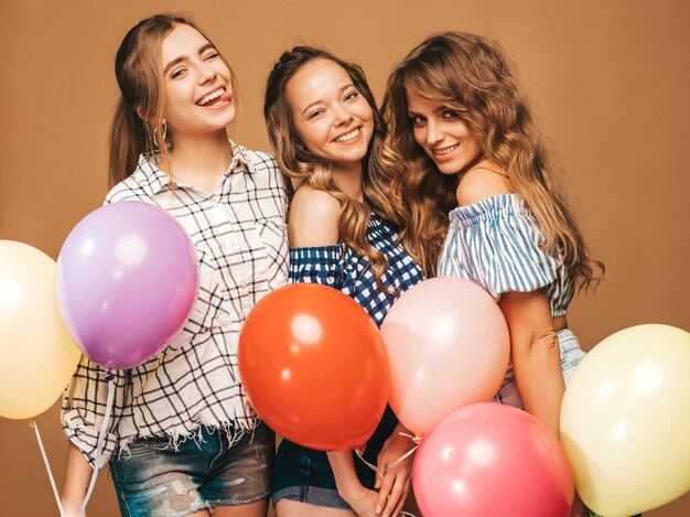 格子縞のシャツの夏服で3人の笑顔の美しい女性。ポーズの女の子。カラフルな風船のモデル。楽しんで、お祝いの誕生日の準備ができて