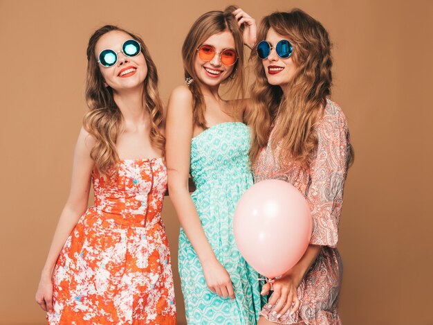 Three smiling beautiful women in checkered shirt summer clothes. Girls posing. Models with colorful balloons in sunglasses. Having fun,ready for celebration birthday or holiday party