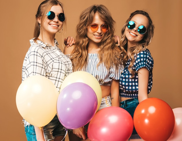 格子縞のシャツ夏服とサングラスで3人の笑顔の美しい女性。ポーズの女の子。カラフルな風船のモデル。楽しんで、お祝いの誕生日の準備ができて