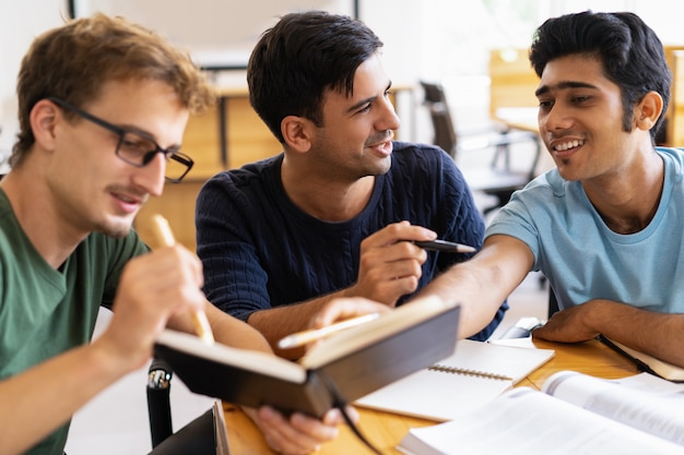 Tre studenti sorridenti studiando e facendo i compiti insieme