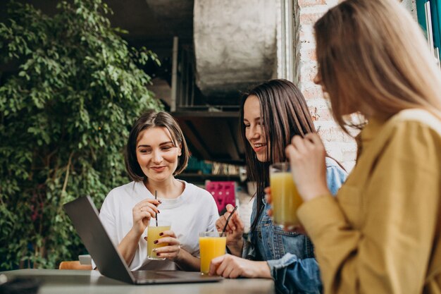 Three students preparing for exam with laptop in a cafe