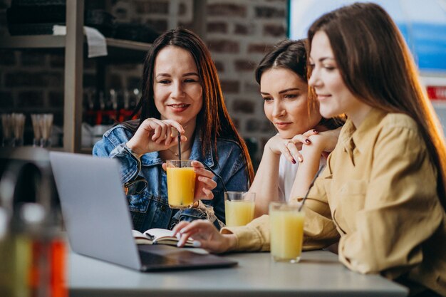 Three students preparing for exam with laptop in a cafe