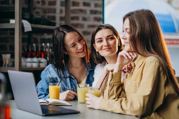 Three students preparing for exam with laptop in a cafe