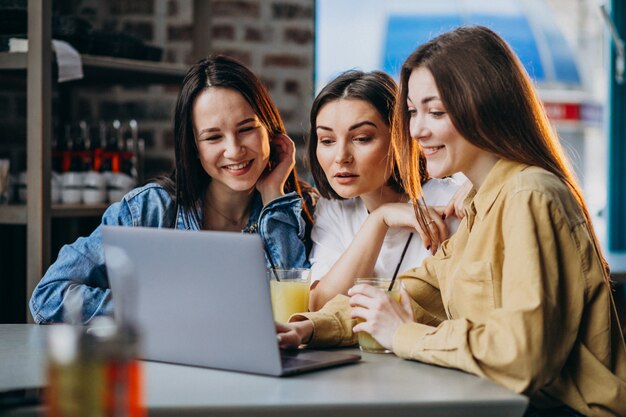 Three students preparing for exam with laptop in a cafe