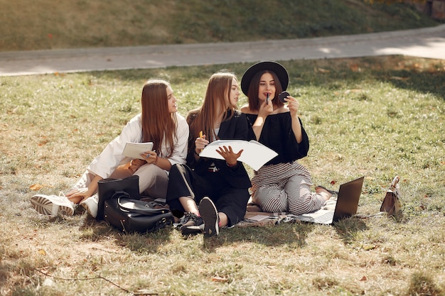 노트북으로 잔디에 앉아 세 학생