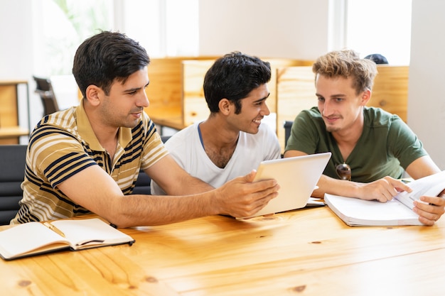 3人の学生が勉強して、タブレットとチャットを使って