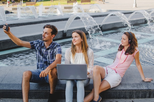 Foto gratuita tre studenti che prendono selfie sulla fontana