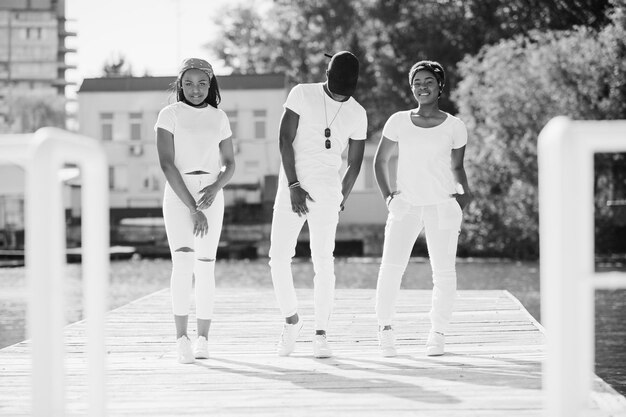 Three stylish african american friends wear on white clothes Street fashion of young black people Black man with two african girls posed