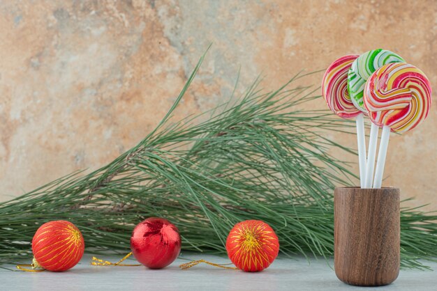 Three sweet colorful lollipops with three Christmas balls on marble background. High quality photo