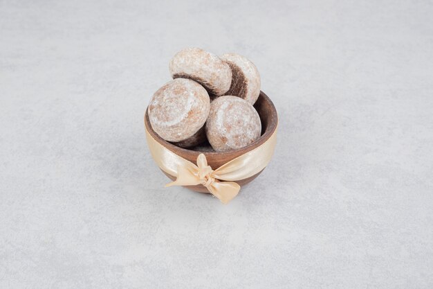 Three sweet cookies with golden bow on wooden bowl