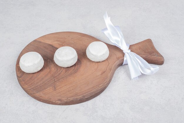 Three sweet cookies with white bow on wooden board. High quality photo