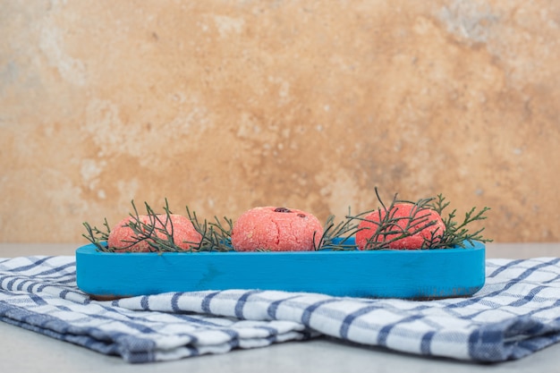 Foto gratuita tre dolci biscotti rotondi rosa sul piatto blu