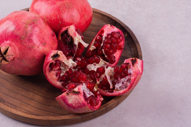 Three sweet pomegranate on wooden board on white.