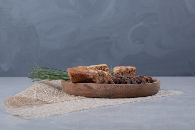 Three sweet slices of pie with star anise on wooden plate. 