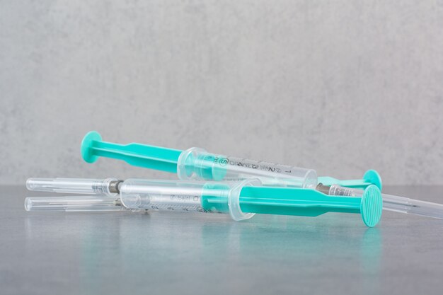 Three syringes with serum on marble surface.