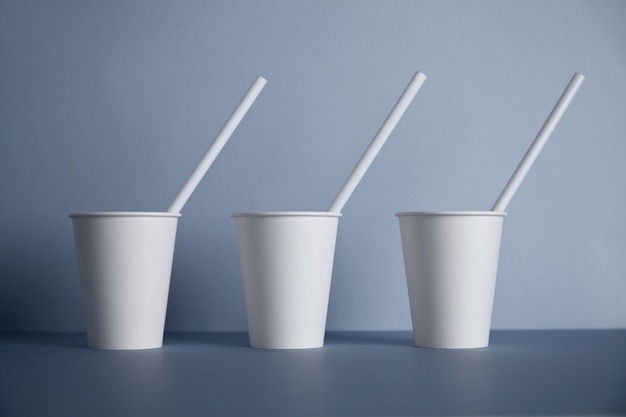 Free photo three take away white paper cups without caps with drinking straws inside presented in center