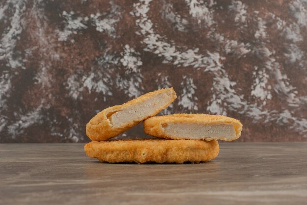 Three tasty chicken nuggets on marble table .