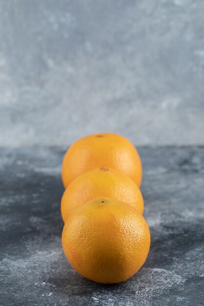 Три вкусных апельсина на мраморном столе.