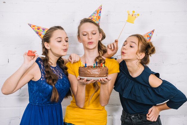 Три подростка подруги дуют свечи на день рождения торт