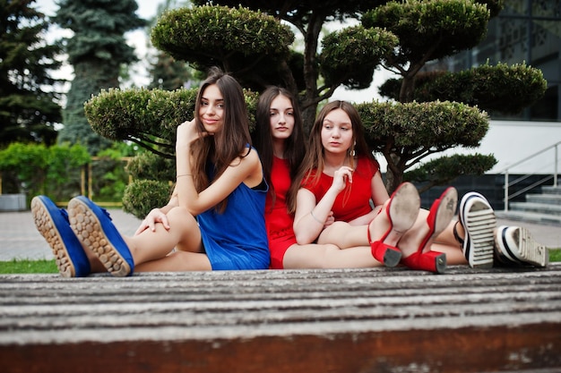 Three teenagers girl in blue and red dresses posed outdoor