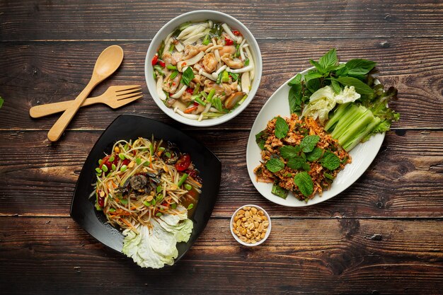 three thai spicy food dishes place on wooden floor